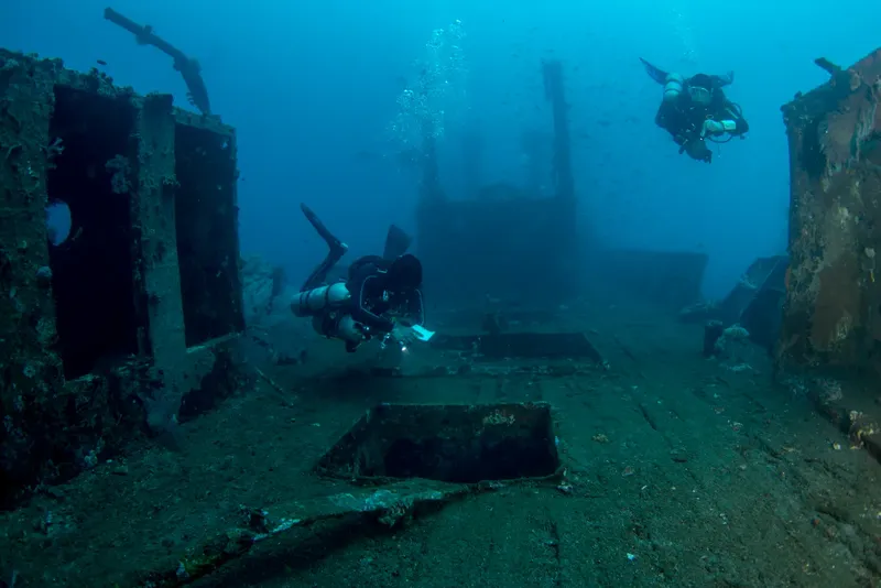 Deux plongeurs explorent l'épave d'un navire sous-marin bleu