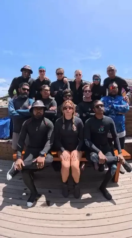 Groupe de personnes souriantes en combinaisons de plongée sur un ponton