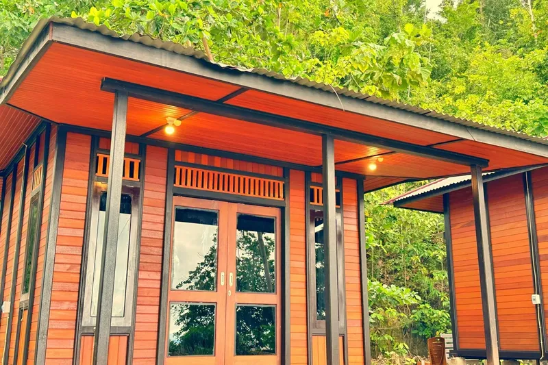 Façade d'un bâtiment en bois avec des ouvertures et de la végétation