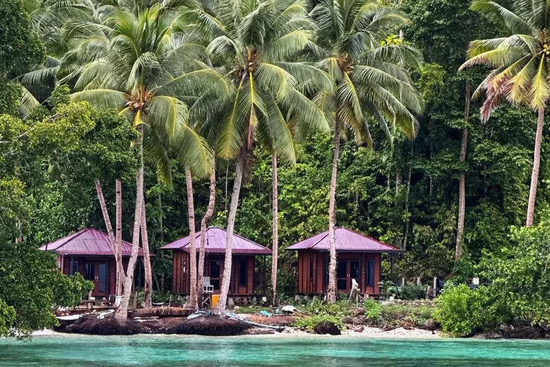 Trois bungalows en bois avec toits rouges au bord de l'eau