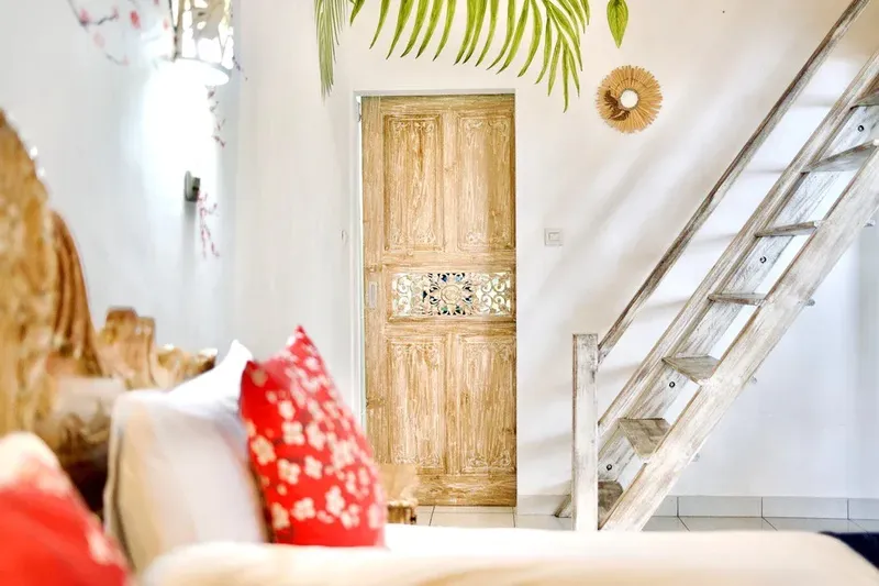 Interieur clair avec porte en bois sculpté et échelle en bois