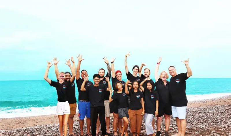 Groupe de personnes souriantes sur une plage de galets ensoleillée