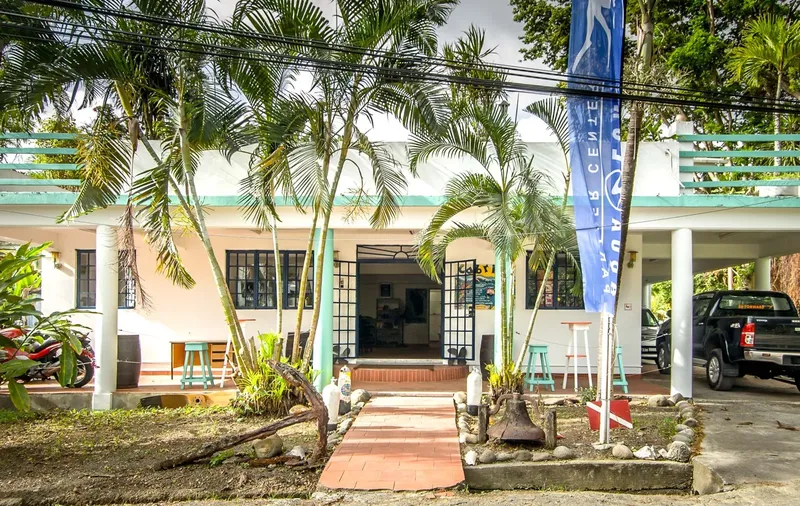 Façade d'un bâtiment avec des palmiers et un parking devant