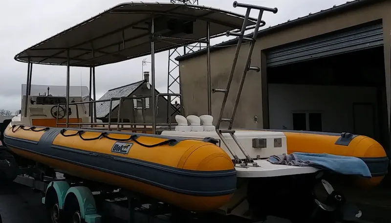 Bateau de plongée jaune et bleu sur remorque devant un bâtiment