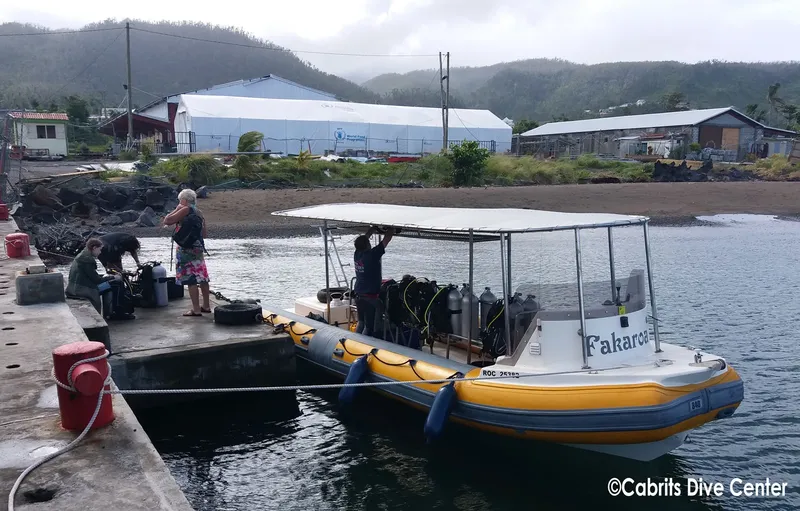 Personnes manipulant du matériel de plongée près d'un bateau amarré au quai