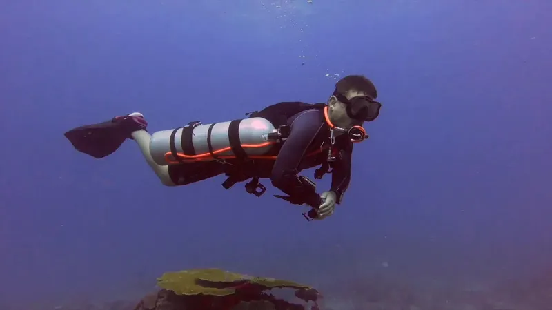 Plongeur en combinaison nageant dans une eau bleue claire