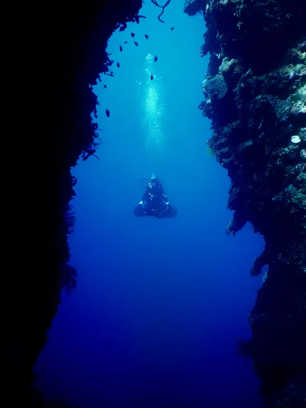 Plongeur explore une grotte sous-marine éclairée par la lumière du soleil