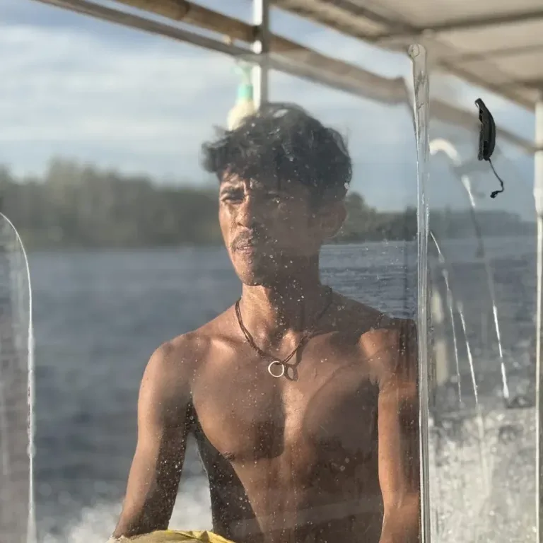 Homme torse nu regardant la caméra depuis un bateau en mer