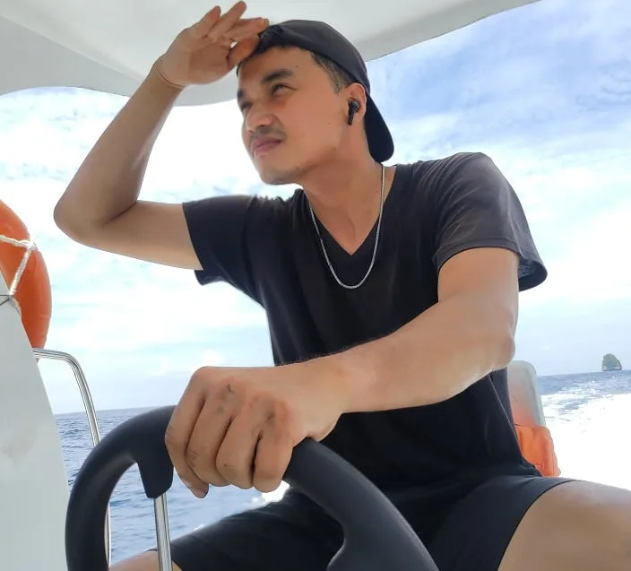 Jeune homme sur un bateau, regardant au loin, en mer