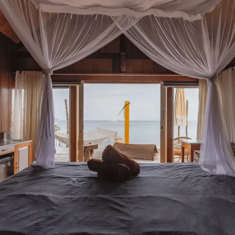 Chambre avec lit à baldaquin donnant sur une vue mer et ponton