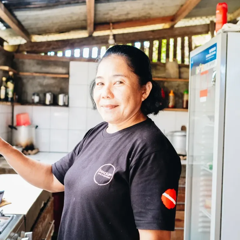 Femme souriante dans un environnement extérieur, portant un t-shirt noir