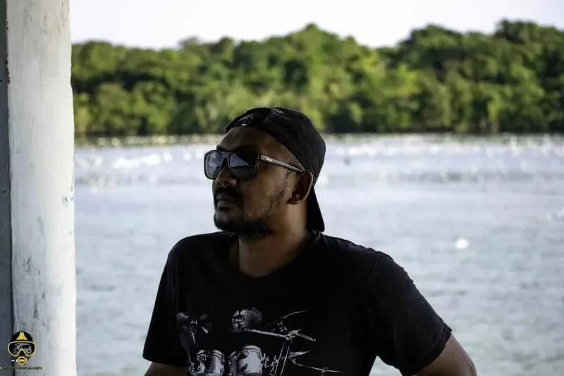Homme portant un t-shirt noir et des lunettes de soleil regarde vers l'horizon