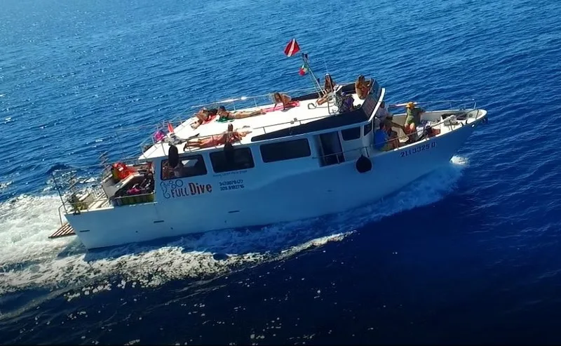 Bateau de plongée blanc avec des passagers, naviguant sur une mer bleue