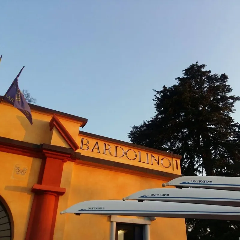 Façade d'un bâtiment orange avec l'inscription Bardolino et des bateaux