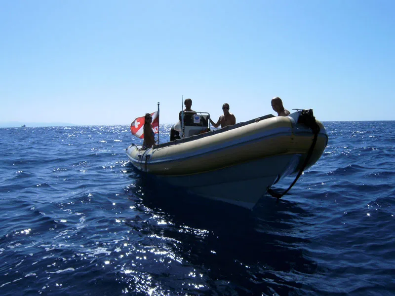 Bateau semi-rigide en mer avec des passagers, ciel bleu et eau calme