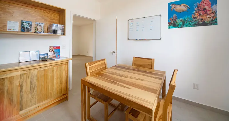 Salle de cours avec table, chaises, tableau blanc et étagères