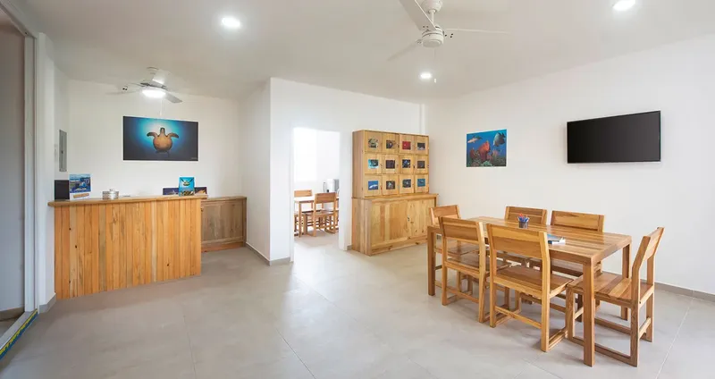 Espace d'accueil lumineux avec comptoir, tables, ventilateurs et décoration marine