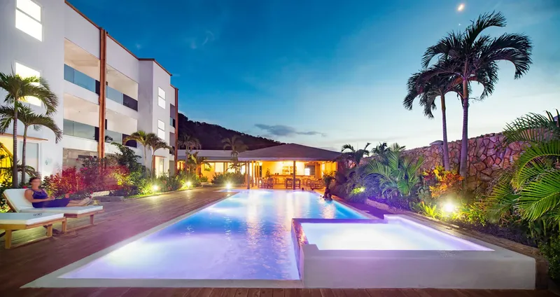 Piscine illuminée avec des personnes se relaxant dans un cadre tropical