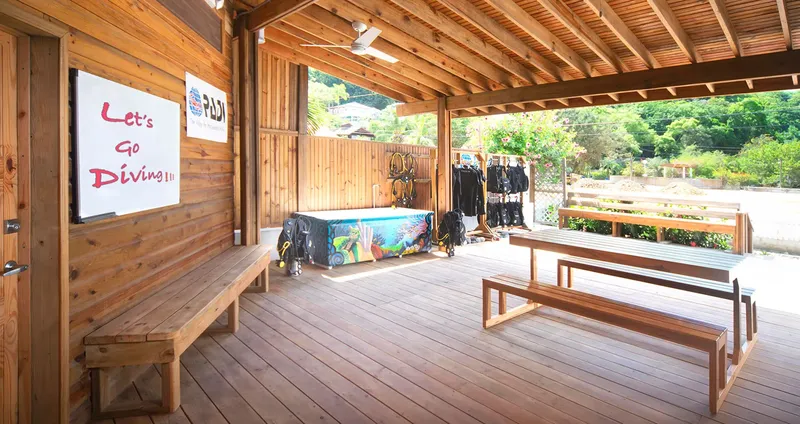 Terrasse bois abritée avec équipement de plongée et bancs en bois