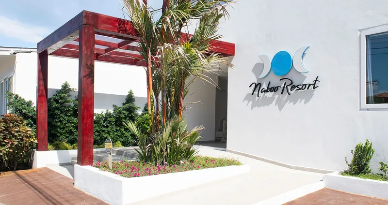 Façade blanche d'un bâtiment avec un auvent rouge et un logo bleu