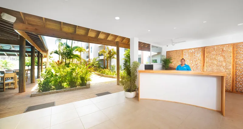 Réception d'un centre avec une employée souriante et un décor tropical