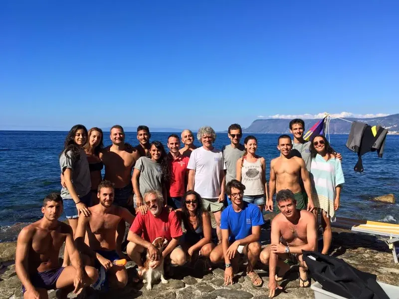 Groupe de personnes souriantes posant devant la mer et le ciel bleu
