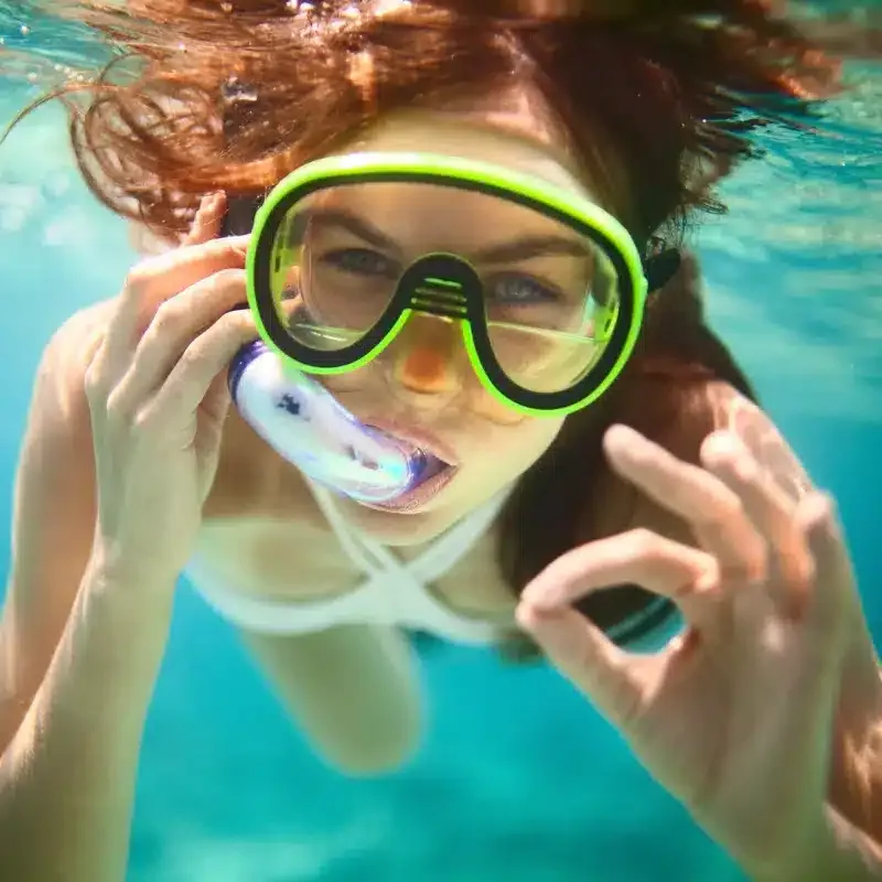 Jeune femme souriante avec masque et tuba sous l'eau turquoise