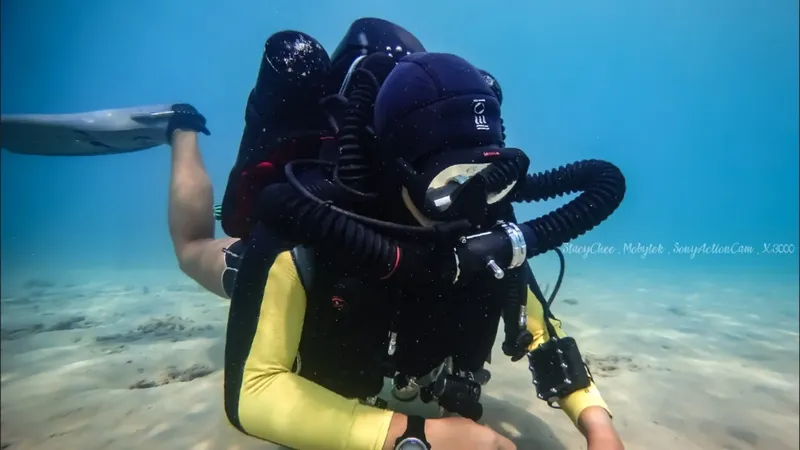 Plongeur en combinaison jaune et noire nageant sous l'eau avec son équipement