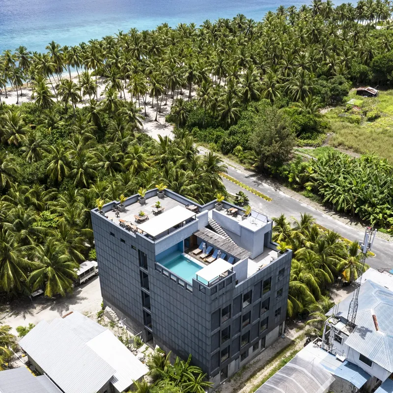 Vue aérienne d'un bâtiment moderne avec piscine et végétation tropicale