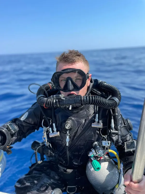 Plongeur équipé regardant la caméra sur fond de mer bleue