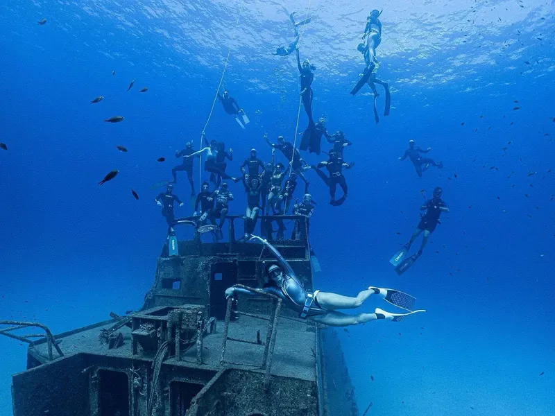 Groupe de plongeurs explore un épave sous-marine bleu profond