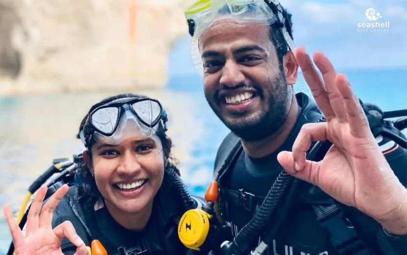 Deux plongeurs souriants, équipés, font des signes de validation