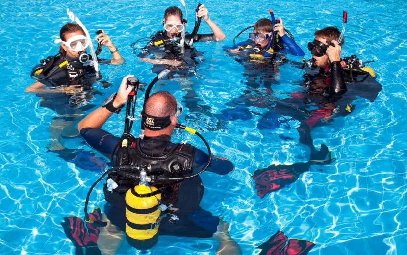 Groupe de plongeurs en formation dans une piscine, équipement complet
