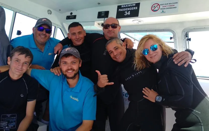 Groupe de personnes souriantes à bord d'un bateau de plongée