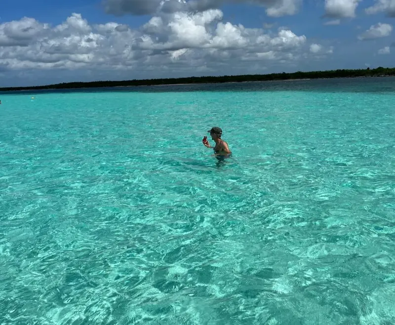 Une personne se tient dans une eau turquoise claire et peu profonde