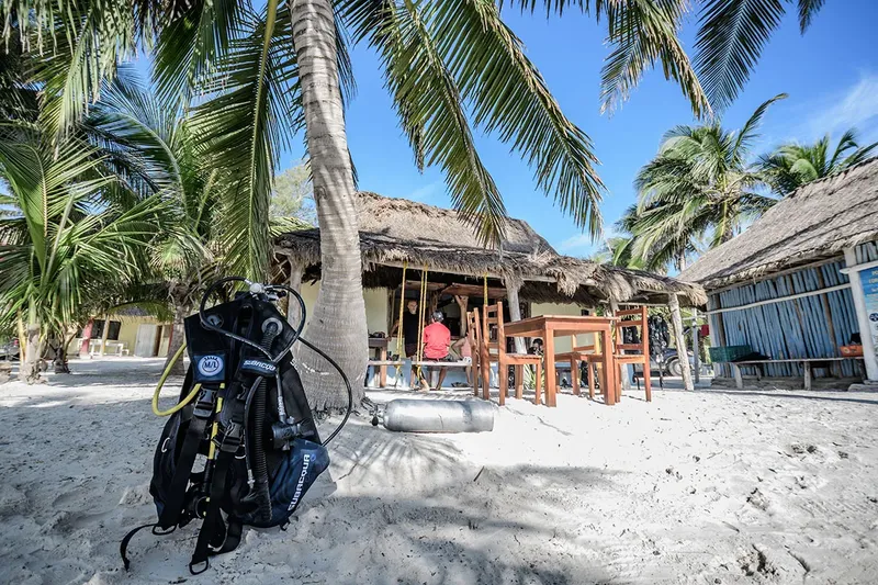 Equipement de plongée sur une plage de sable blanc devant des bungalows