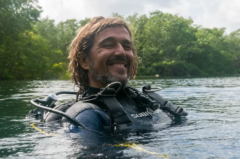 Plongeur souriant émerge de l'eau avec son équipement complet