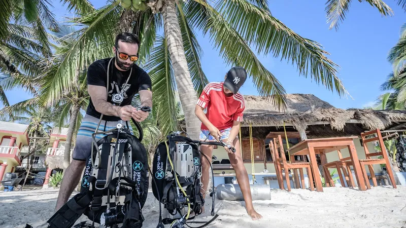 Deux plongeurs préparent leur équipement sur une plage tropicale ensoleillée