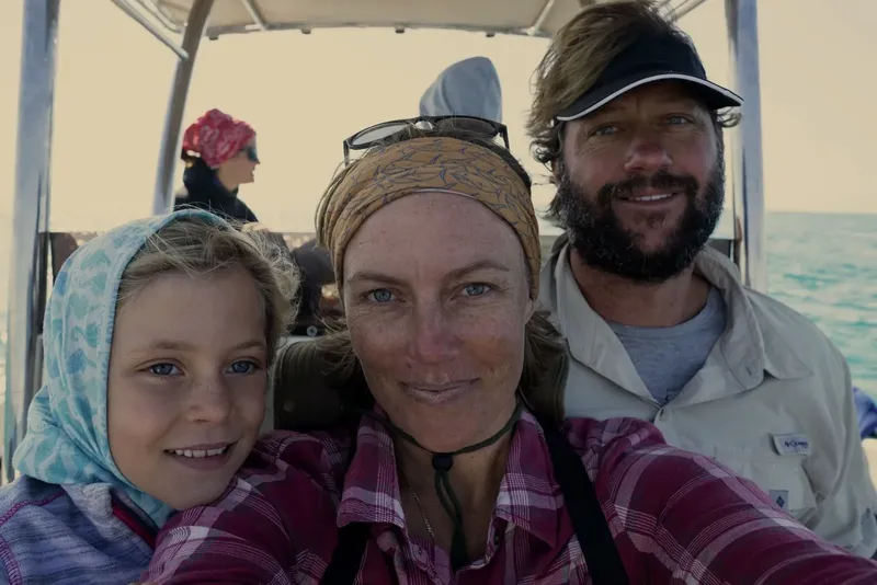 Trois personnes souriantes sur un bateau en mer, ciel bleu