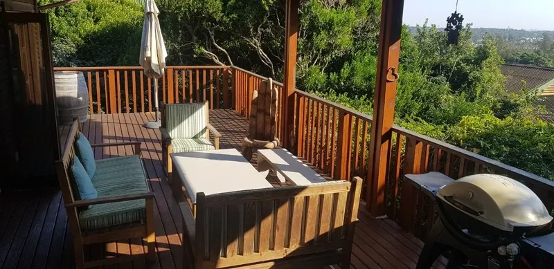 Terrasse en bois avec mobilier de jardin et barbecue vue sur végétation