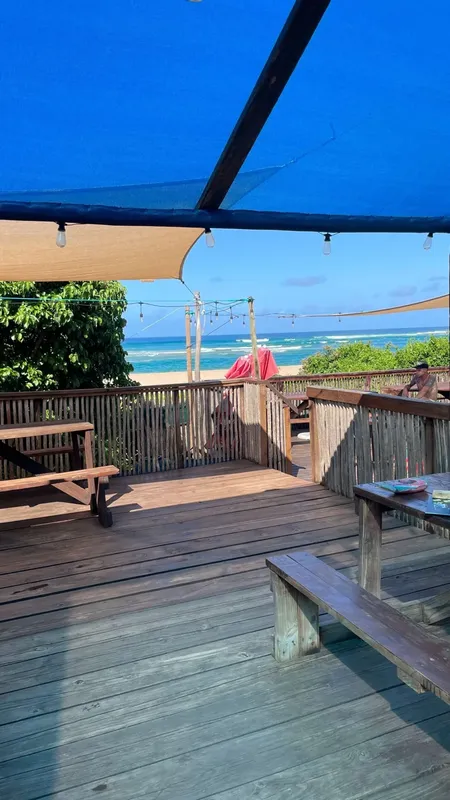 Terrasse en bois avec vue sur la mer et quelques personnes assises