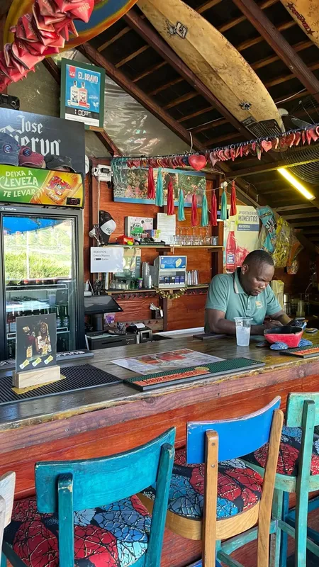 Un homme derrière un comptoir de bar coloré, ambiance tropicale décontractée