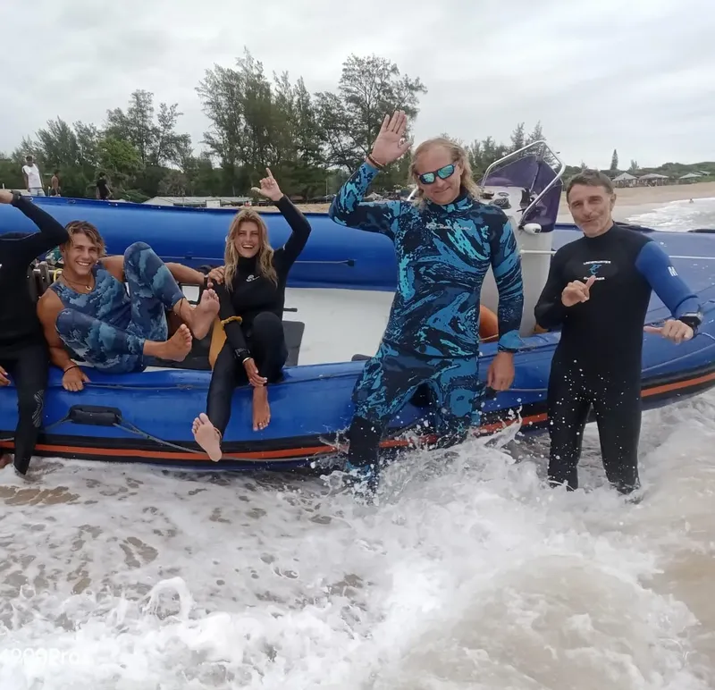 Quatre personnes en combinaison de plongée sortent d'un bateau bleu