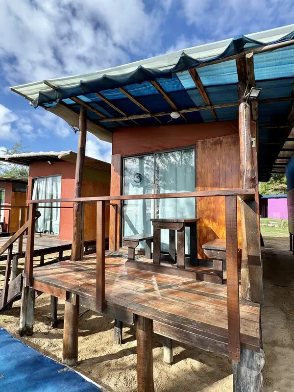 Petites cabanes en bois sur pilotis avec toit bleu et terrasse