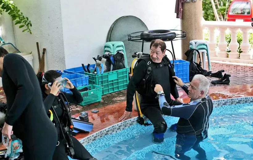Préparation de plongeurs en combinaison près d'une piscine avec du matériel