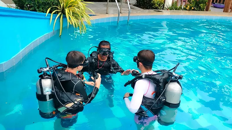 Trois plongeurs en formation dans une piscine, équipement complet visible