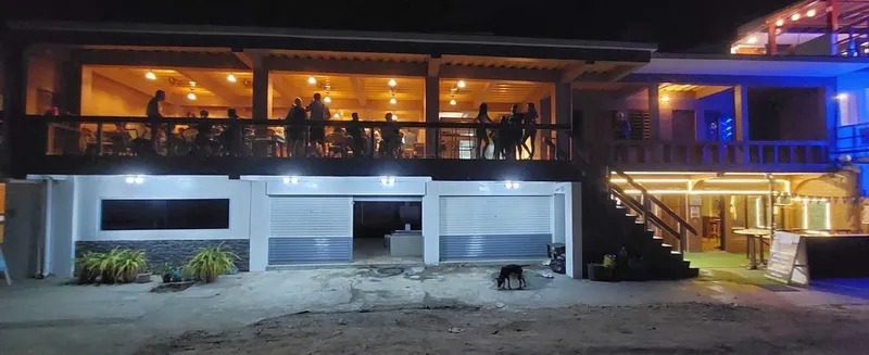 Bâtiment éclairé avec des personnes sur une terrasse et un chien