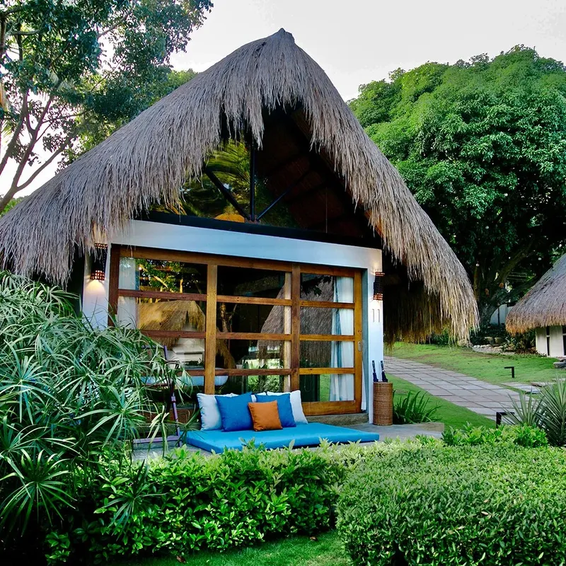 Bâtiment avec toit de chaume, terrasse et végétation tropicale luxuriante