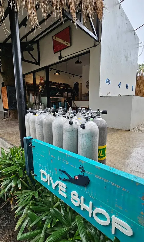 Bouteilles de plongée devant un magasin de plongée avec enseigne turquoise