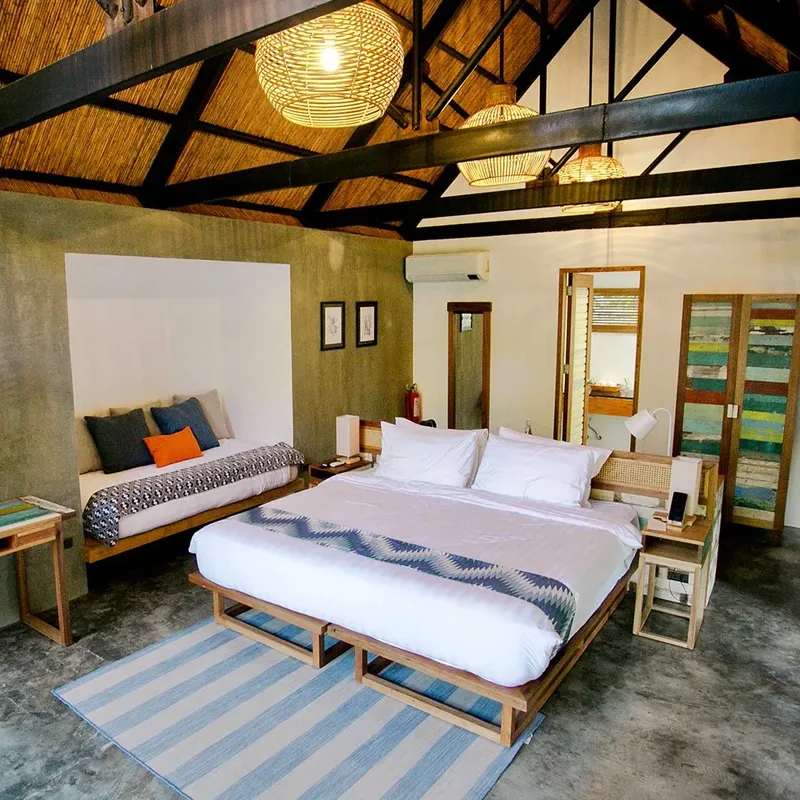 Chambre d'hôtel avec lit double, canapé et décoration tropicale